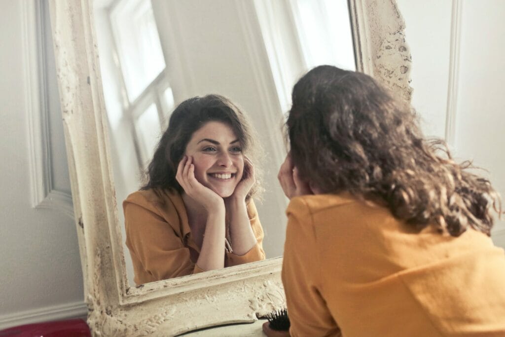 Γυναίκα που κοιτάζει στον καθρέπτη και χαμογελά
