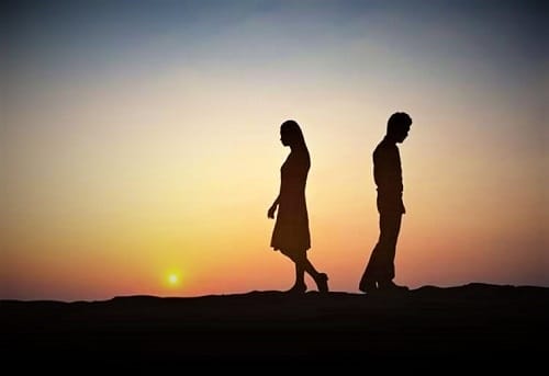 Ένας άνδρας και μια γυναίκα κινούνται προς την αντίθετη κατεύθυνση μετά το χωρισμό με θέα το ηλιοβασίλεμα.