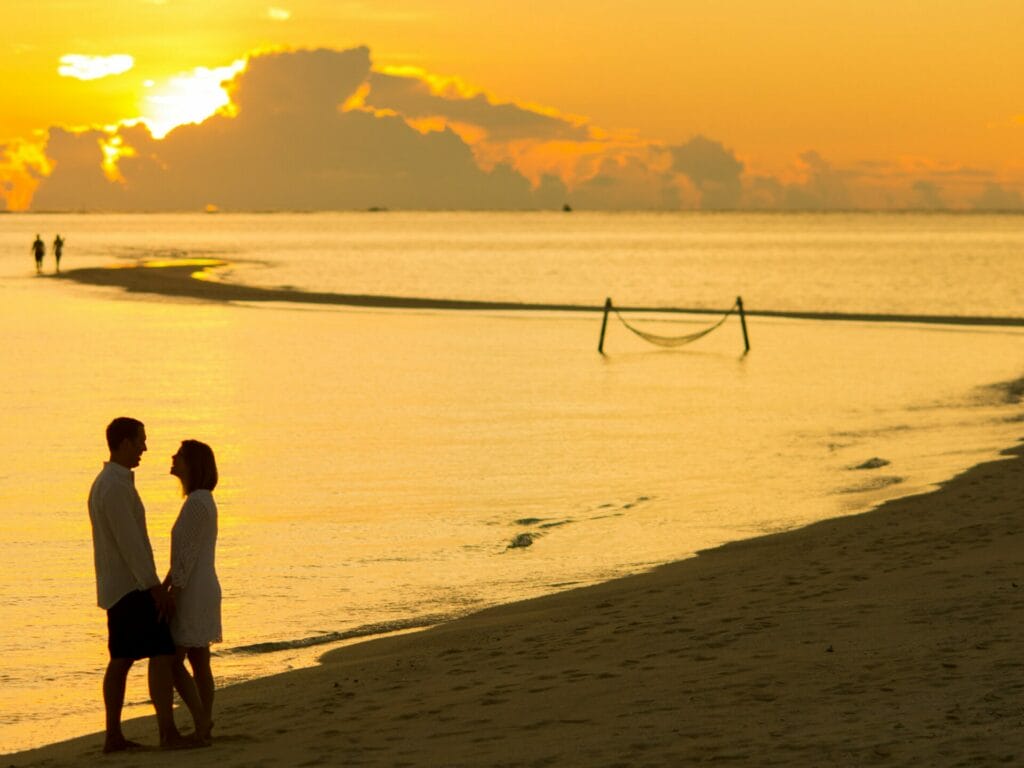 Ζευγάρι (άνδρας και γυναίκα) στην παραλία με φόντο το ηλιοβασίλεμα