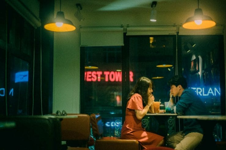 Γυναίκα και άνδρας καθησμένη σε καφετέρια ο ένας απέναντι στον άλλον πίνουν χυμο και κοιτάζονται στα μάτια