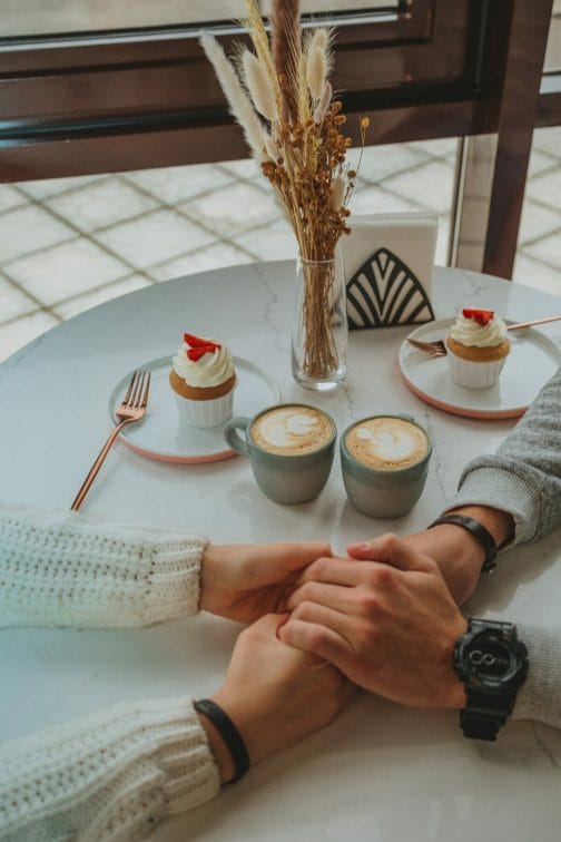 Ζευγάρι με πιασμένα χέρια πάνω σε ένα τραπέζι καφετέριας